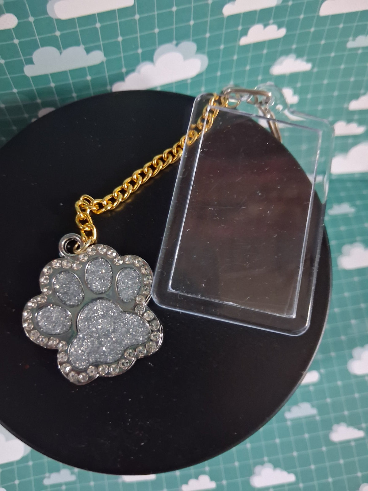 Close-up of the silver glitter paw charm with diamond-style detailing beside the clear acrylic photo frame
