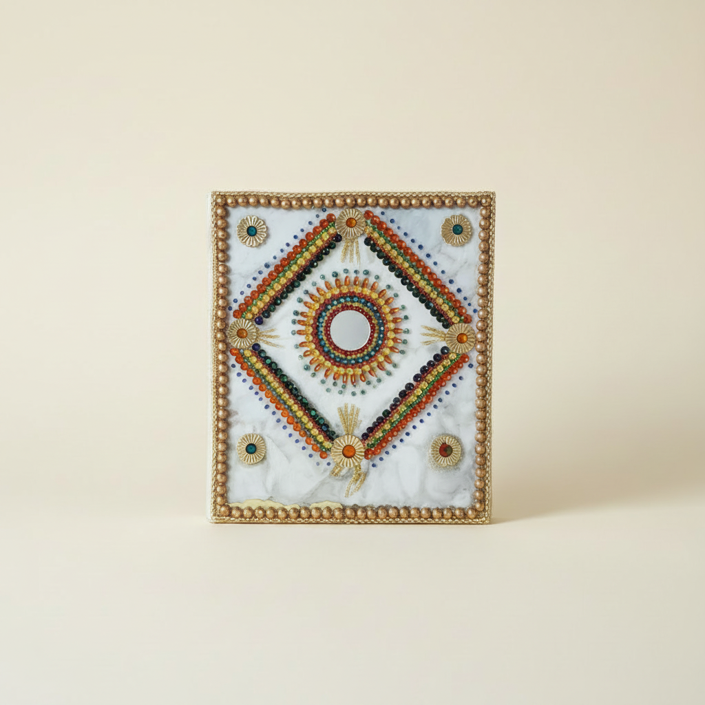 Square handmade journal with gold beaded frame and bead mandala with mirror centre on marble-look board, on a clean cream background